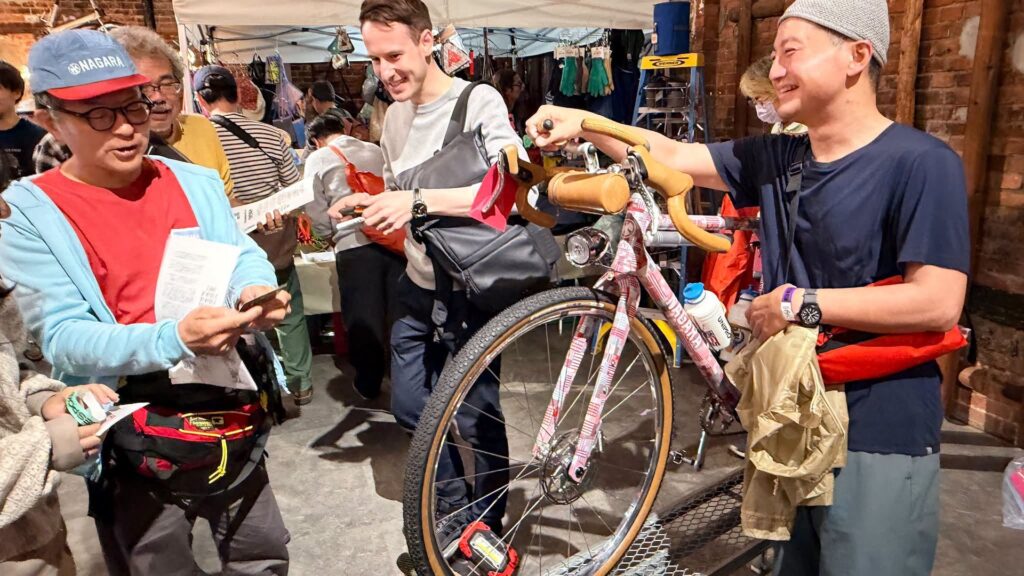 Nagara stands with bicycle and attendees at Bespoked Japan